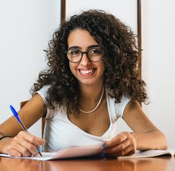 student girl with glasses and curly brunette hair sitting and doing classes