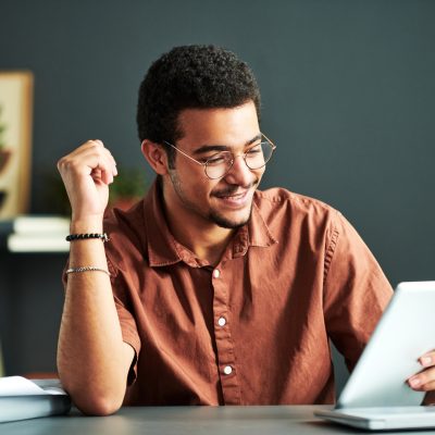 Young smiling student of online course of study looking at tablet screen